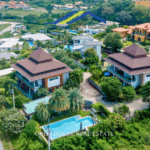 Two modern two-story apartment buildings at Khao Yai Apartments Hua Hin surrounded by tropical gardens and a large shared swimming pool.