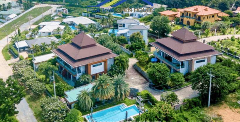 Two modern two-story apartment buildings at Khao Yai Apartments Hua Hin surrounded by tropical gardens and a large shared swimming pool.