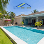 Exterior view of a private Hua Hin family home with large swimming pool, outdoor gym area, and tropical garden surrounded by privacy walls.