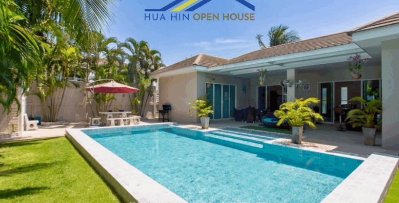 Exterior view of a private Hua Hin family home with large swimming pool, outdoor gym area, and tropical garden surrounded by privacy walls.